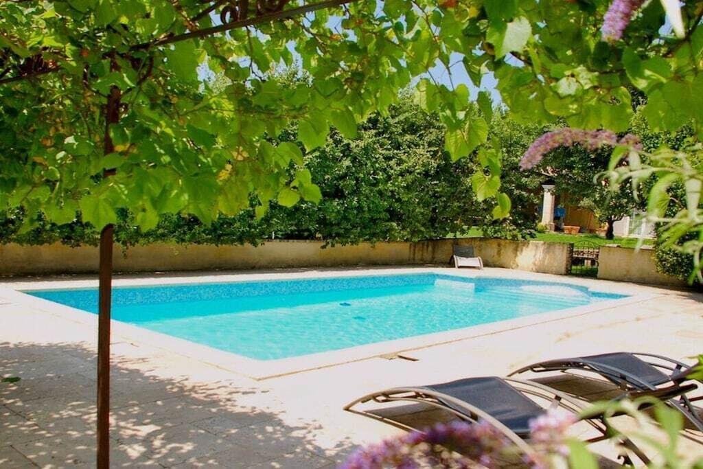 A swimming pool with a clear blue water surface, surrounded by a paved deck.
