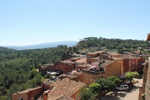 A village with terracotta-roofed buildings, a clear sky, and a hilly backdrop. - Holiday apartment with 2 bedrooms (Roussillon)