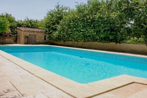 A rectangular swimming pool with a tiled edge, surrounded by a stone wall and a hedge. - Holiday apartment with 2 bedrooms (Roussillon)
