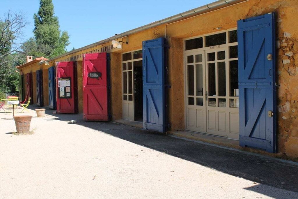 A building with multiple doors and windows, some with shutters.