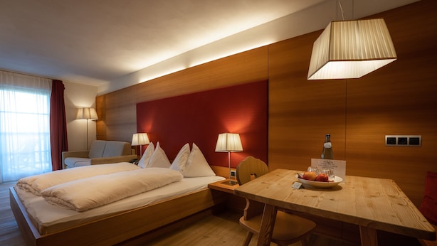 A hotel room with a bed, bedside tables, a desk with a chair, and a dining table with fruit. - Room 2 with Mountain View (Badia)