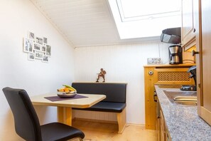 Cocina compacta con zona de comedor, una pequeña banca y una cafetera.