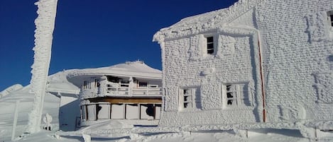 Un edificio cubierto de nieve con un balcón y una chimenea.