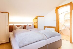 Un dormitorio con cama, armario y baño visible a través de una puerta abierta.