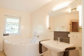 Ein modernes Badezimmer mit einer freistehenden Badewanne, einem Waschbecken und einem großen Spiegel.