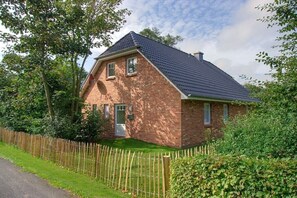 Eingeschossiges Backsteinhaus mit geneigtem Dach, einer Haustür und einer kleinen Veranda.