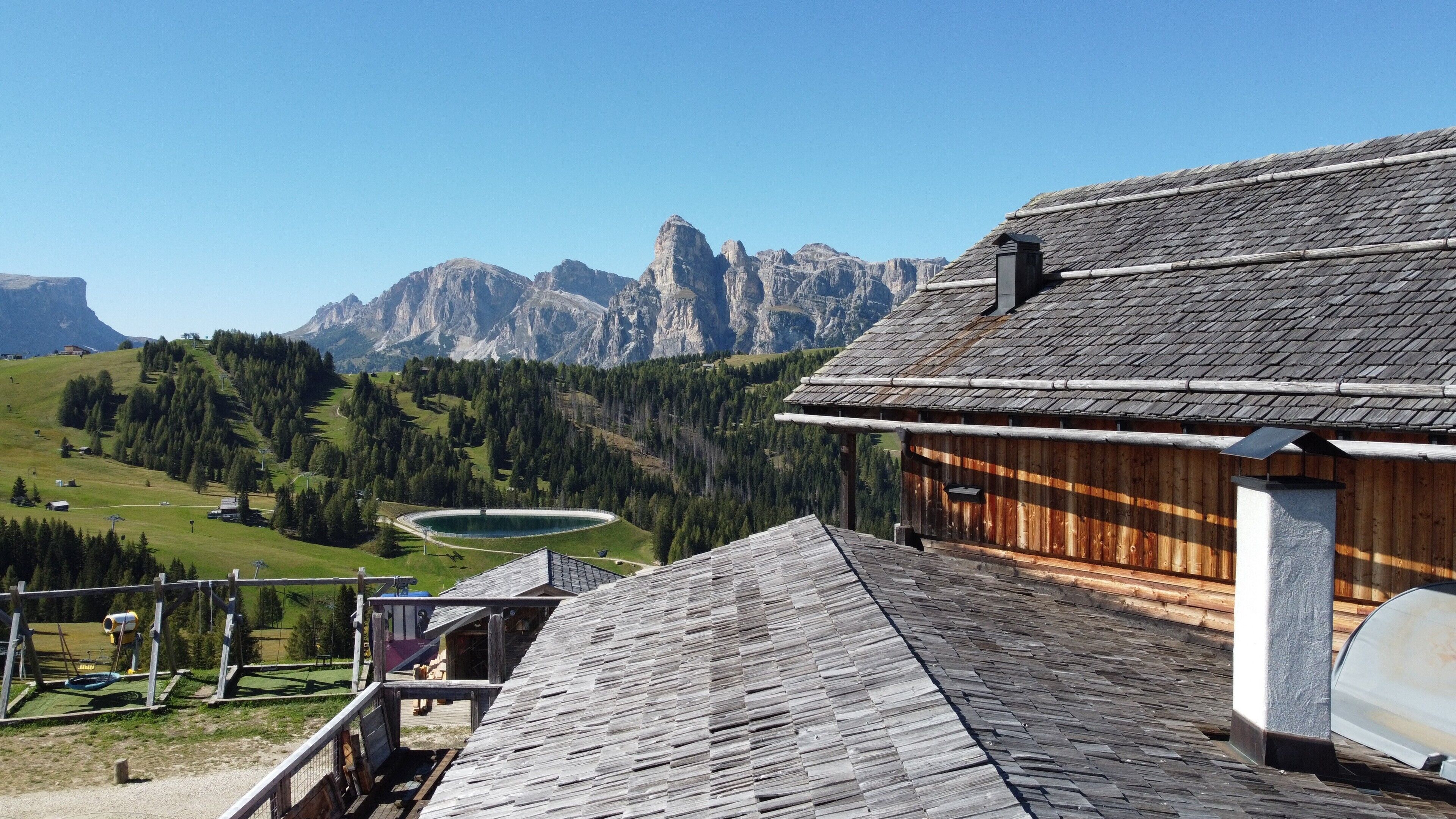 Un chalet de montagne avec une façade en bois, une vue sur un lac et, en arrière-plan, des montagnes escarpées.