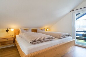Un dormitorio con cama de madera, dos mesitas de noche y una ventana con vistas.