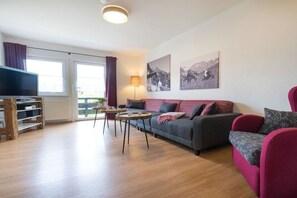 Una sala de estar con un sofá, dos sillones, una mesa de centro y un televisor.