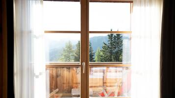 Une porte coulissante à cadre en bois donnant sur un balcon et offrant une vue sur le paysage extérieur.