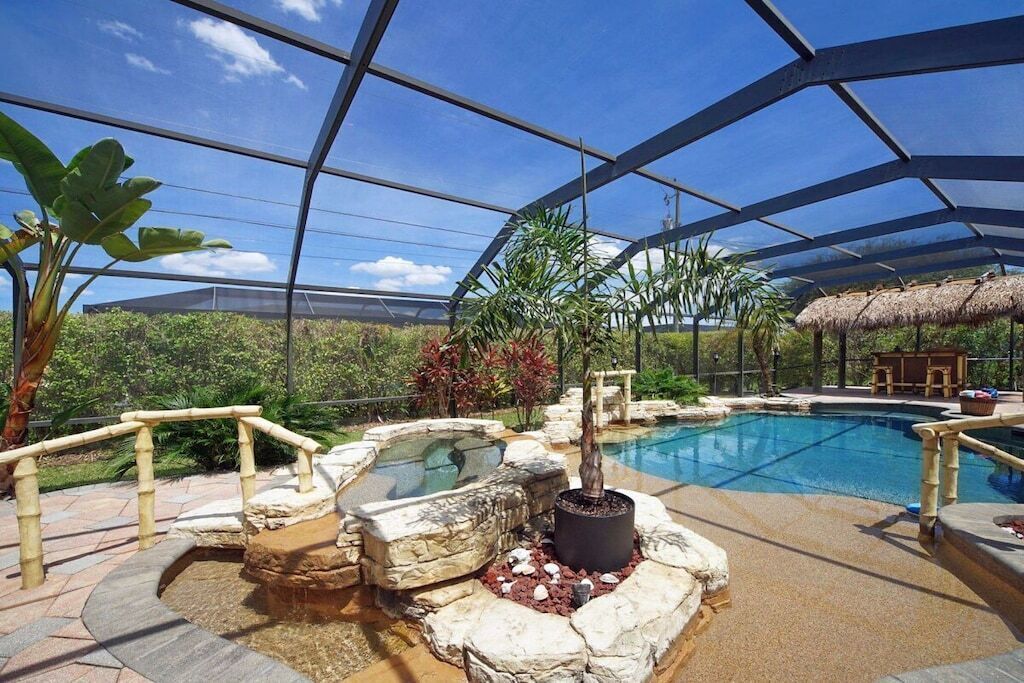 An indoor swimming pool with a glass ceiling, surrounded by rock formations and plants.