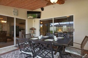 An outdoor dining area with a table and chairs, a ceiling fan, and a view of the outside. - CCVS - Villa Tropical Dream (Cape Coral SW Florida)