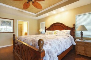 A bedroom with a wooden bed, two bedside lamps, a ceiling fan, and a window with blinds. - CCVS - Villa Tropical Dream (Cape Coral SW Florida)
