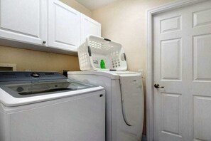 Un'area lavanderia con lavatrice, asciugatrice e una porta bianca.