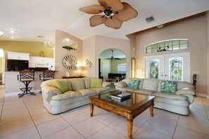 A living room with a sofa, coffee table, and a ceiling fan. - CCVS - Villa Tropical Dream (Cape Coral SW Florida)