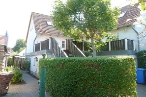 A residential property with a paved driveway, a wooden fence, and a well-maintained hedge. - Holiday apartment in Wiek with barbecue (Wiek)