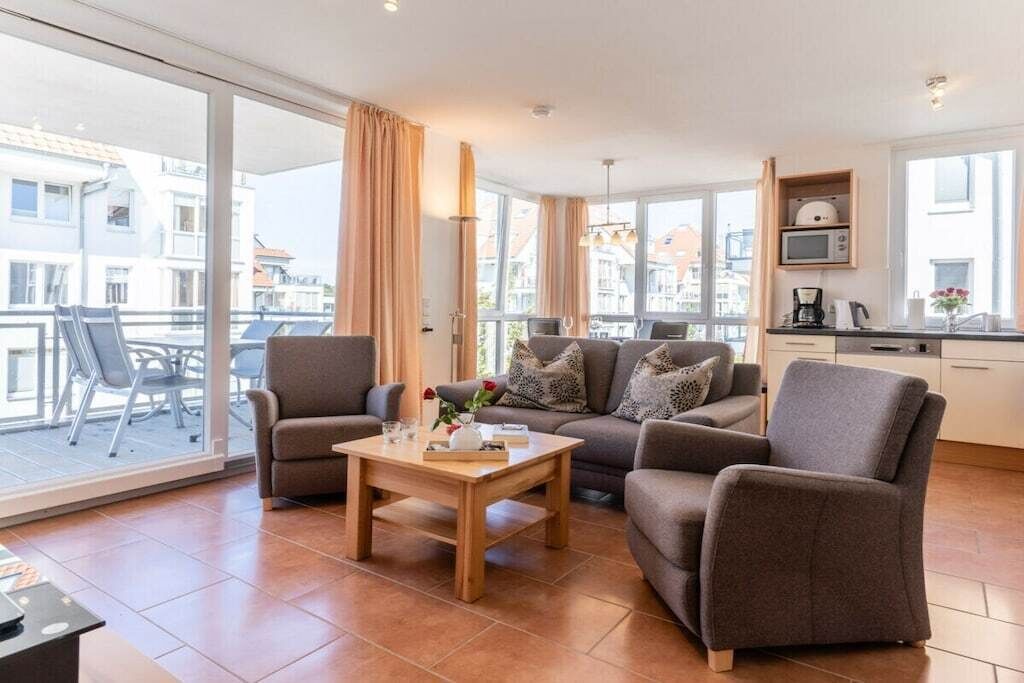 Una sala de estar moderna con un conjunto de sofá, una mesa de centro y vista a la ciudad a través de amplios ventanales.