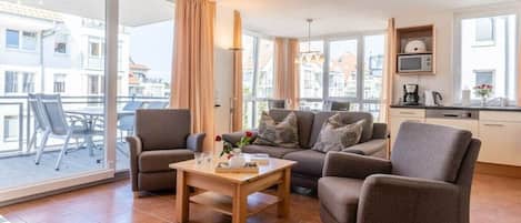 Una sala de estar moderna con un conjunto de sofá, una mesa de centro y vista a la ciudad a través de amplios ventanales.