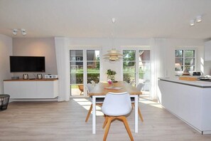 Una cocina moderna con comedor, ventanas amplias y un televisor de pantalla plana.
