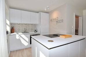 Eine moderne Küche mit weißen Schränken, einer gemusterten Spritzschutzleiste und einer Arbeitsplatte mit integriertem Herd.