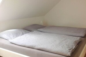 Una cama con un colchón blanco y dos almohadas.