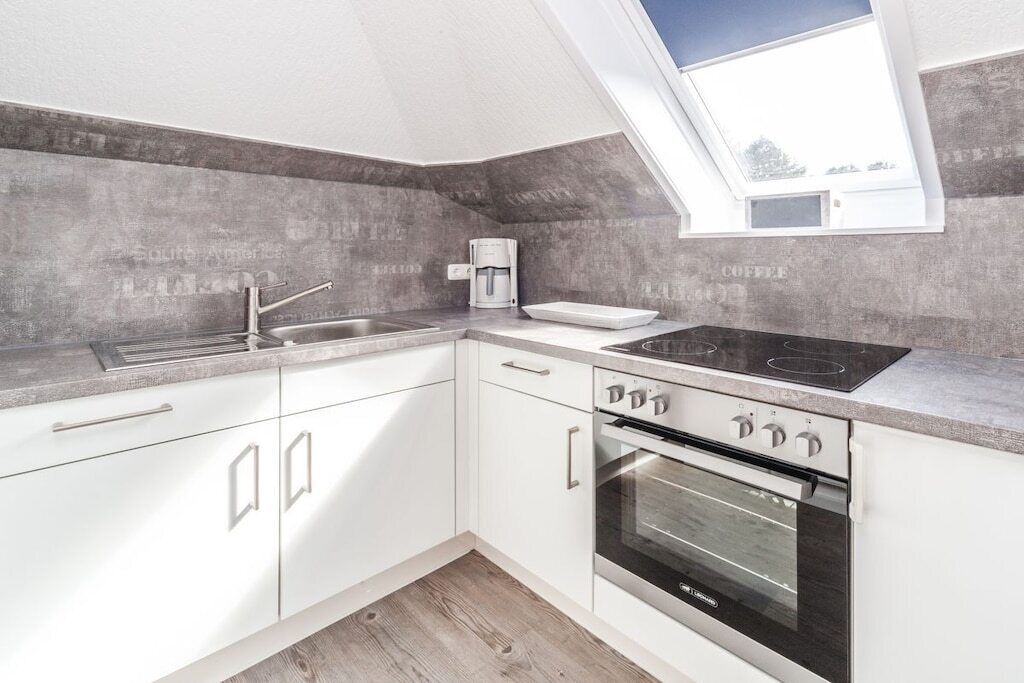 A modern kitchen with a built-in oven, a coffee maker, and a skylight.