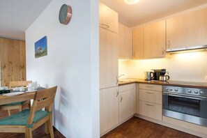 Eine kleine Küche mit Holzausstattung, einem Edelstahlbackofen und einem Essbereich mit Holztisch und Stühlen.