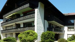 Un edificio de varios pisos con balcones, una columna de piedra y cielo despejado.
