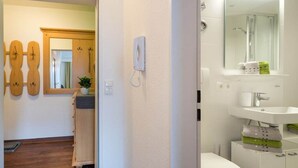 Un baño con lavamanos blanco, espejo y zona de ducha.