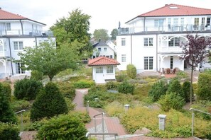 A residential area with two-story houses, a garden with various plants, and a small white house with a red roof. - Villa Bernstein Apt. 32 (Binz)