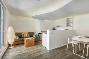 Ein moderner Wohnraum mit Essbereich, Küchenzeile und einer Sofaecke mit Kissen.
