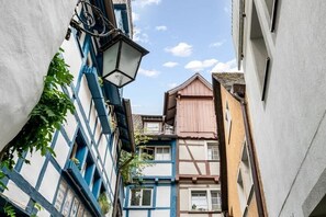 Eine schmale Gasse mit traditionellen Fachwerkhäusern, einer Straßenlaterne und einem klaren Himmel.