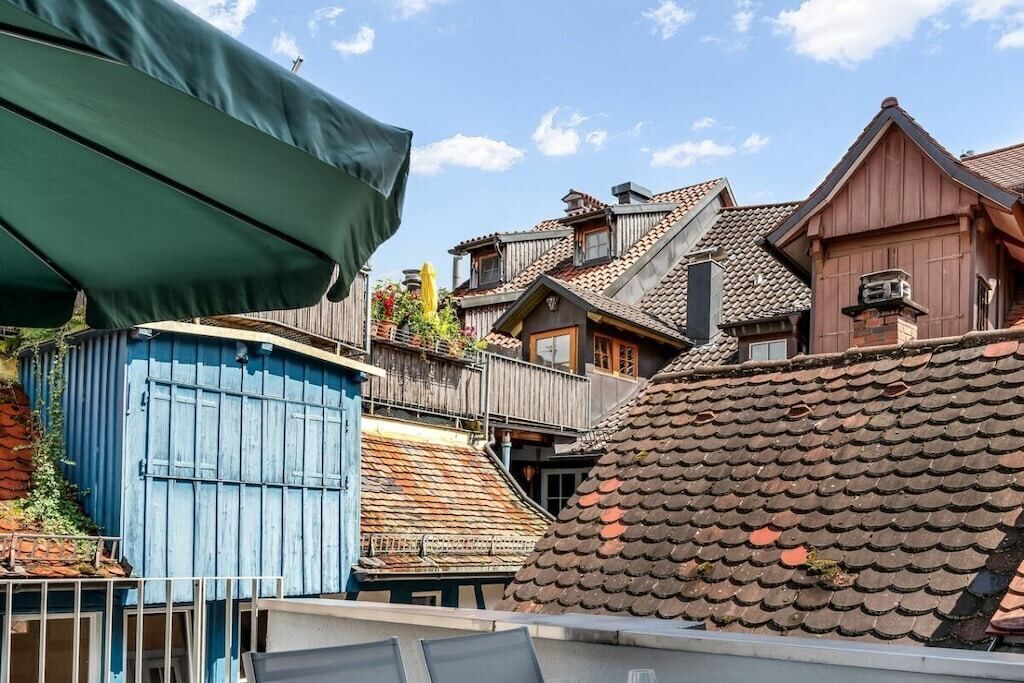 Ein traditionelles Holzgebäude mit geneigtem Dach, einer blauen Tür und einem Balkon mit Geländern.