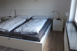 Ett modernt sovrum med en säng, två sängbord och ett litet bord.
