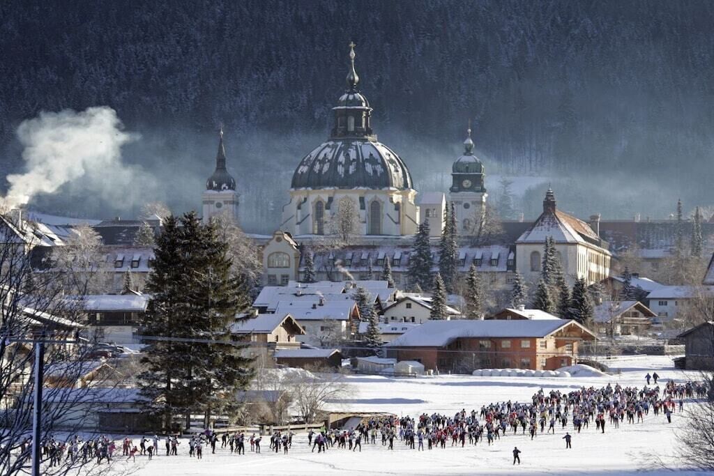 A snowy town with a prominent church and a crowd of people in the foreground.