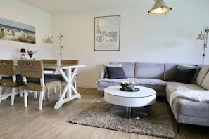 A living room with a grey sofa, white coffee table, wicker chairs, and a map on the wall. - Holiday apartment with 2 bedrooms (Büsumer Deichhausen)