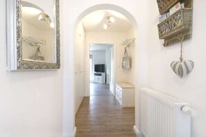 A hallway with a mirrored wall, a radiator, and a basket shelf with items. - Holiday apartment with 2 bedrooms (Büsumer Deichhausen)