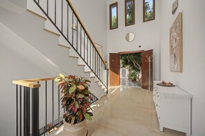 Ein modernes Interieur mit Treppe, einem Topfpflanzen, einem Essbereich und Blick durch eine offene Tür.