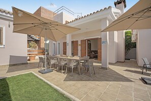 An outdoor patio with a table and chairs, umbrellas, and a view of a building in the background. - Holiday home 'Villa Nakupenda' with private pool, Wi-Fi and air conditioning (Chiclana de la Frontera)