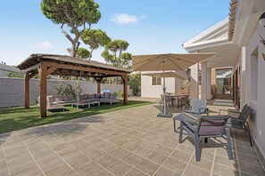 Un espace patio agrémenté d’une pergola, de sièges d’extérieur et d’une table avec des chaises.