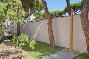 A fenced garden area with artificial grass, trees, and a concrete wall. - Holiday Home 'Villa Brasilia' with Private Pool, Wi-Fi and Air Conditioning (Chiclana de la Frontera)