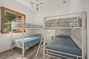 Una habitació amb literes, una finestra amb vista a vegetació i un penjador.