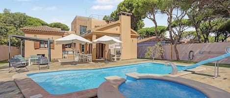 Une piscine avec un jacuzzi, un espace salon extérieur et une terrasse couverte.