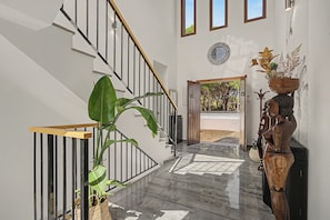 A modern interior with a staircase, a wooden sculpture, and a large plant. - Holiday Home 'Villa Brasilia' with Private Pool, Wi-Fi and Air Conditioning (Chiclana de la Frontera)