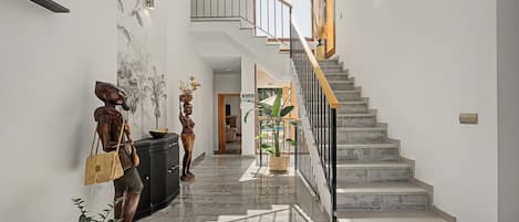 A modern interior with a marble staircase, a wall-mounted light fixture, and a decorative sculpture.