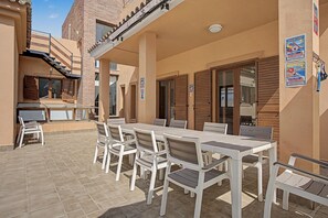 Un patio al aire libre con una mesa, sillas, un muro de ladrillo y una puerta de madera.