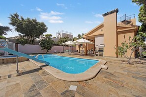 A swimming pool with a slide, lounge chairs, and umbrellas. - Holiday Home 'Villa Brasilia' with Private Pool, Wi-Fi and Air Conditioning (Chiclana de la Frontera)