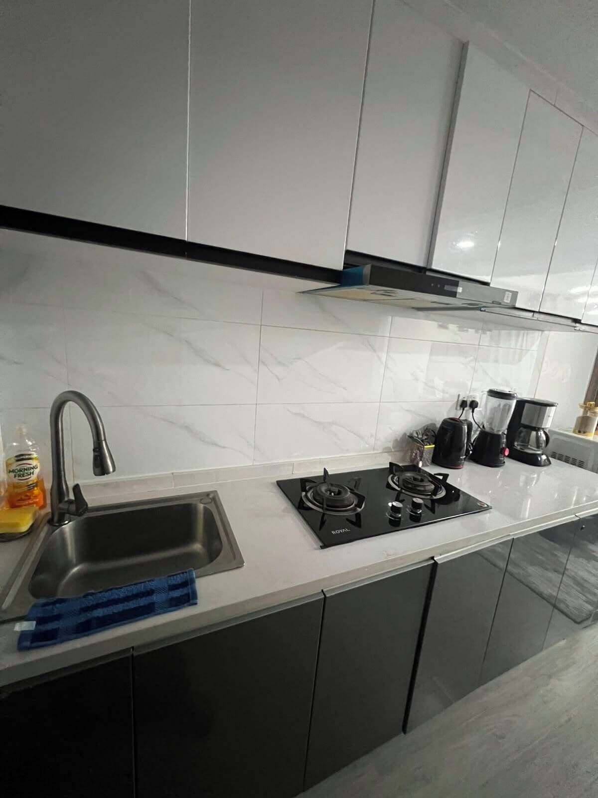 A modern kitchen with a gas stove, sink, and black cabinets.