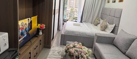 Una sala de estar moderna con un sofá, una mesa de centro con flores, un televisor y una estantería.