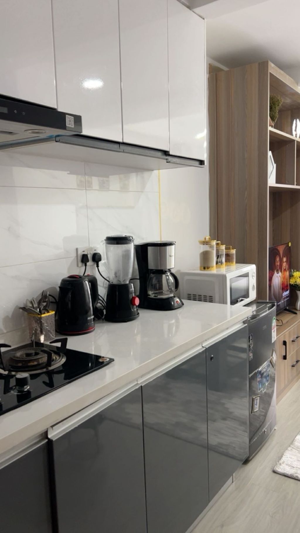 Una cocina moderna con estufa a gas, cafetera, licuadora y microondas.